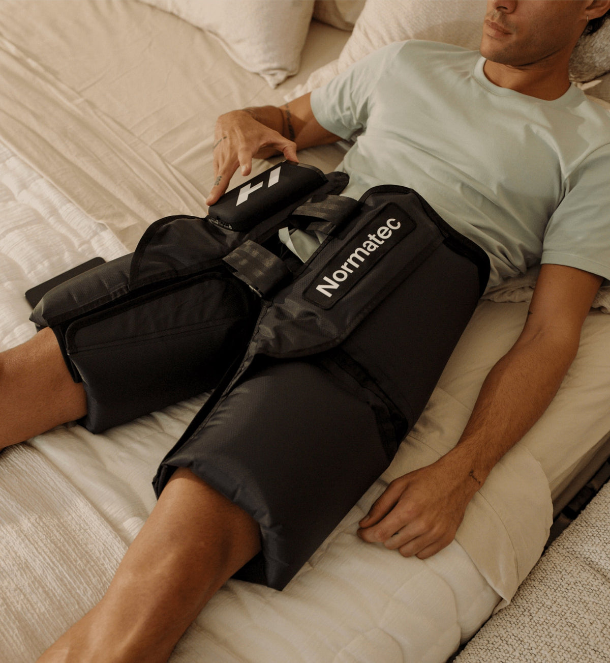 Person bruger Normatec Premier Hips i et soveværelse
