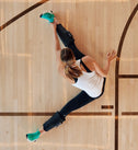 Kvinde strækker ud på en basketballbane med Normatec Lower Legs