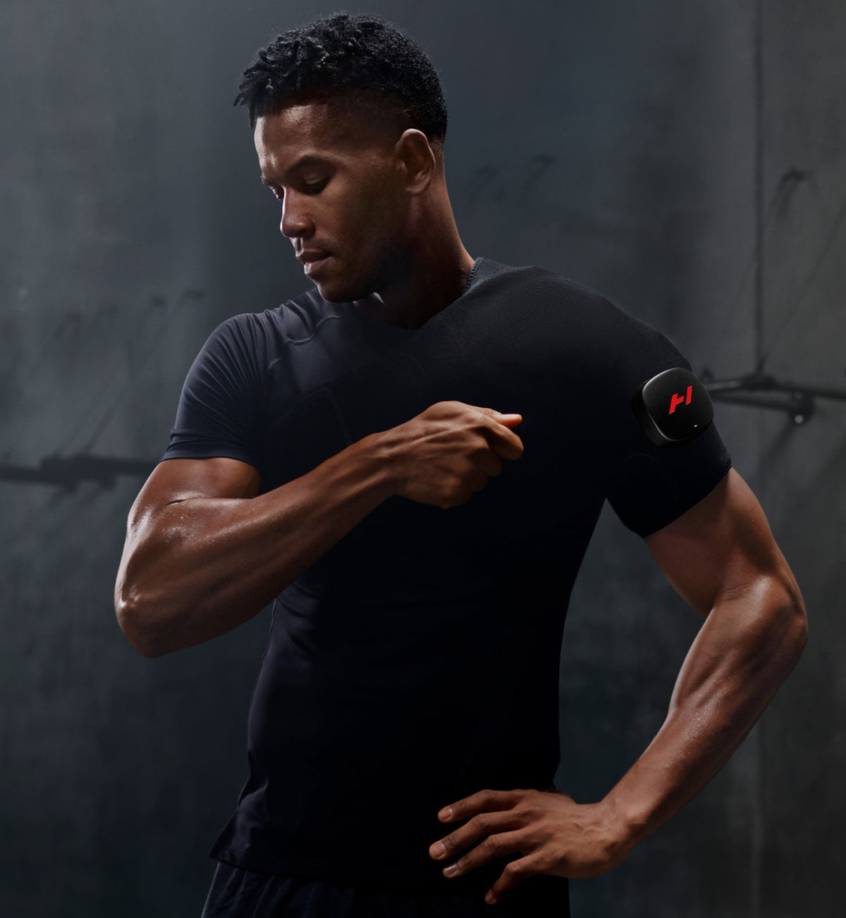 Man wearing a black t-shirt adjusting his venom 2 shoulder against a dark background